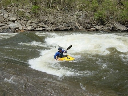 A person battling rapids in a kayak